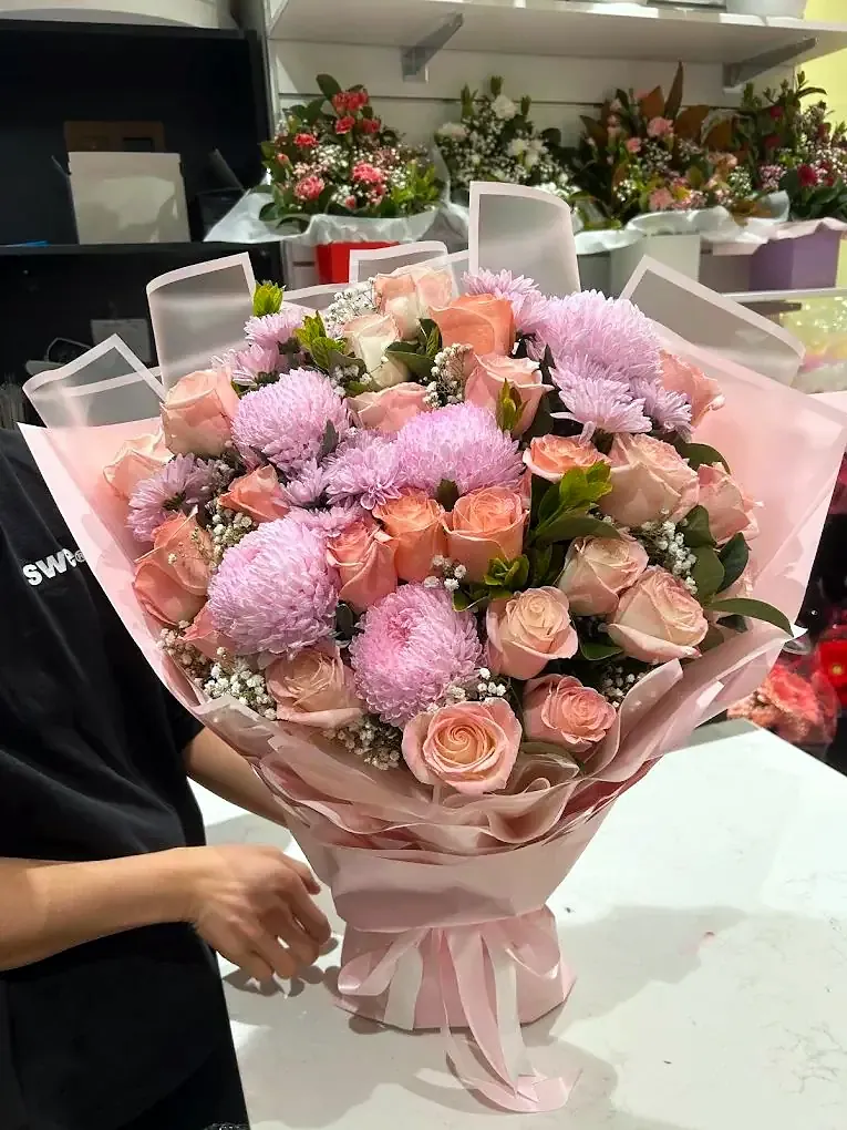 Ready-made bouquet of pink roses and chrysanthemums, held up in the shop