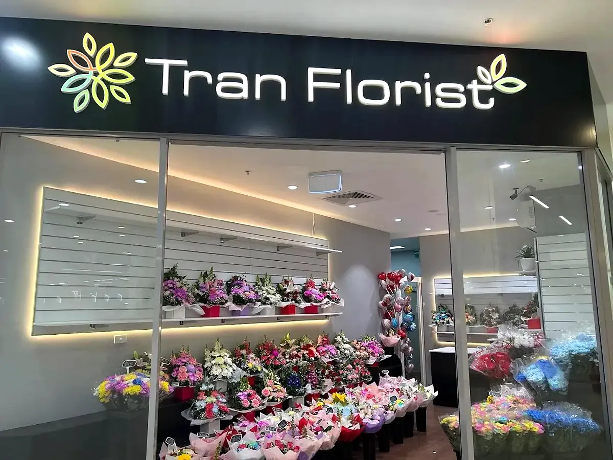 Tran Florist shopfront: the black sign with glowing lettering above the lit bouquet wall